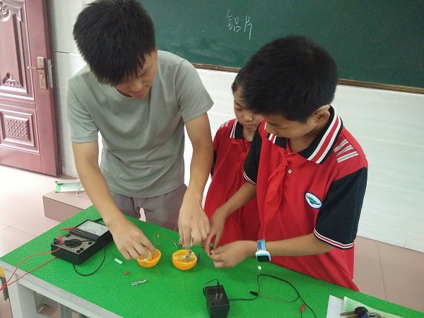 (图为陈军老师带领同学们做科学实验"水果发电")